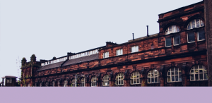 ein dunkles Universitätsgebäude aus Backstein mit halbrunden Fenstern.