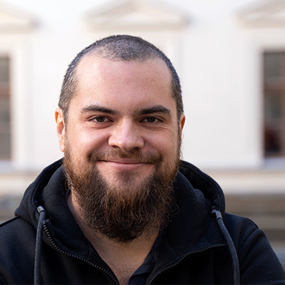 Photo of Timotheus Hell: He is wearing a black pullover and smiling into the camera